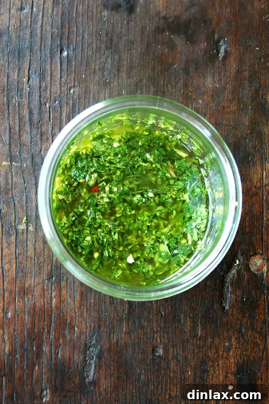The freshly prepared vibrant green herb sauce, a perfect blend of basil, garlic, red wine vinegar, and red pepper flakes, contained in a small glass jar.