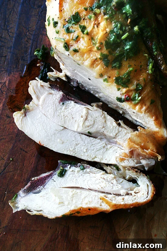 A perfectly sliced piece of roasted chicken breast, revealing its moist and tender interior, invitingly ready to eat.
