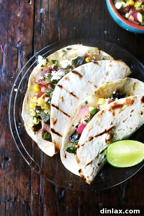 Savory grilled poblano corn salsa enhances any steak taco meal, offering a burst of fresh flavors. Steak Tacos with Homemade Grilled Poblano and Corn Salsa, topped with avocado and sour cream, perfect for a vibrant summer meal.