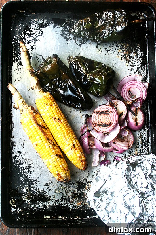 Smoky Grilled Poblano and Corn Salsa Tacos 4 Perfectly grilled poblano peppers, corn, and red onions cooling on a sheet pan, ready for the next step of salsa preparation.