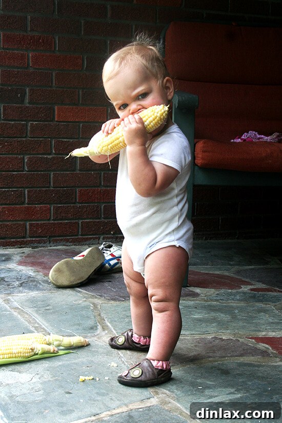 Smoky Grilled Poblano and Corn Salsa Tacos 7 A child, affectionately dubbed a 'corn thief,' happily eating a kernel of grilled corn, showing the universal appeal and deliciousness of this summer vegetable.