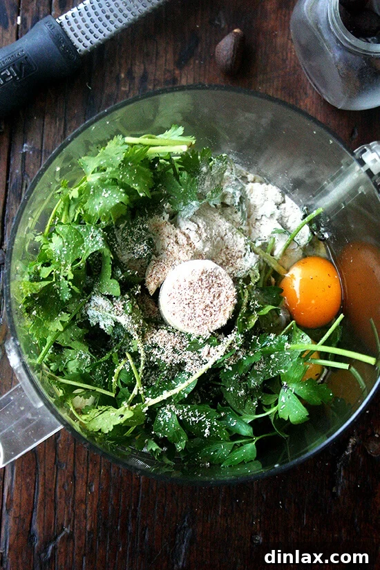 Greens, herbs, and spices being processed in a food processor to create the fritter batter.