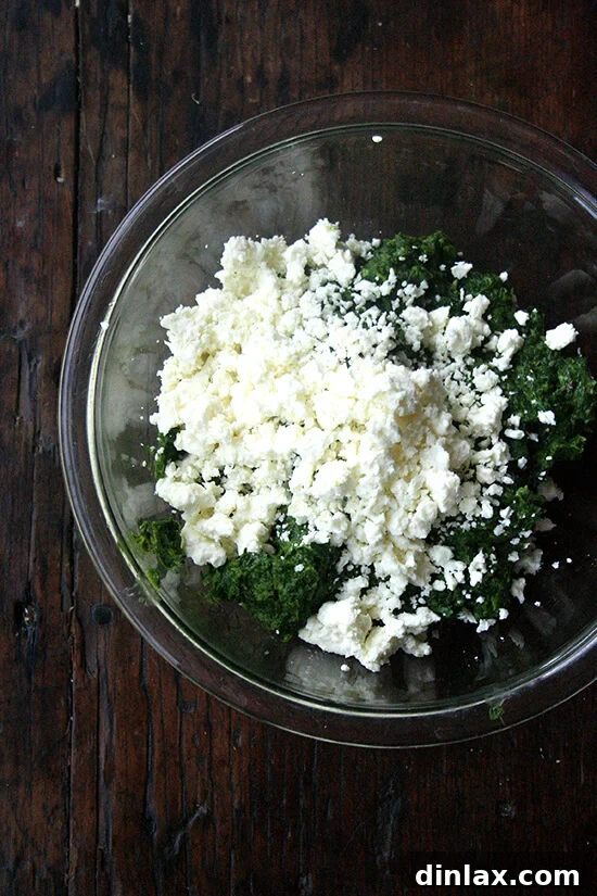 Crumbled feta cheese being folded into the green fritter batter for added flavor and texture.