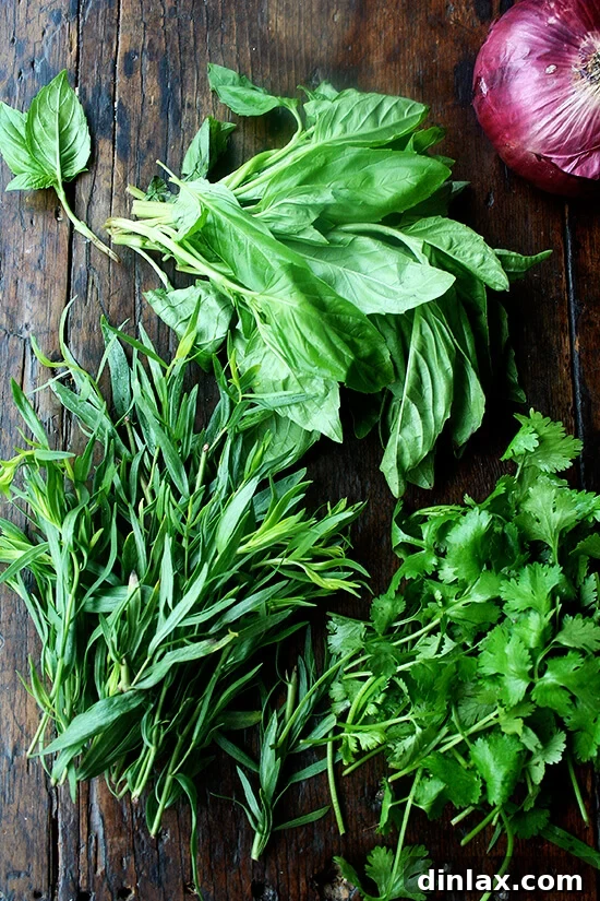 Freshly chopped herbs including basil, tarragon, cilantro, and mint, ready to be added to the chicken salad.