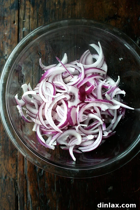 Thinly sliced red onion macerating in vinegar, a crucial step for mellowing its sharpness.