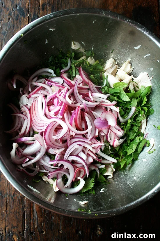 Macerated red onions, softened and flavored with vinegar, are added to the salad mixture.