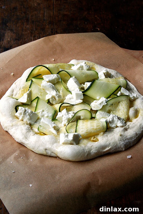 Burrata Basil Summer Squash Pizza 7 The Zucchini Anchovy pizza, meticulously prepared and ready for the oven, resting on a parchment-lined pizza peel, promising a delicious outcome.