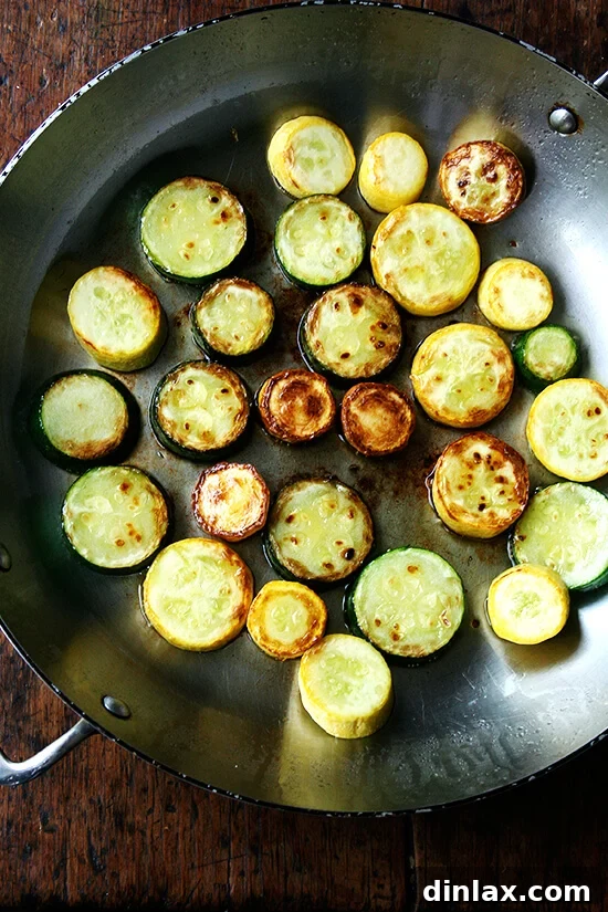 Bright Zucchini Sauté with Mint, Basil and Pine Nuts 3 Close-up of zucchini and summer squash rounds sautéing to a golden brown in a skillet with olive oil.