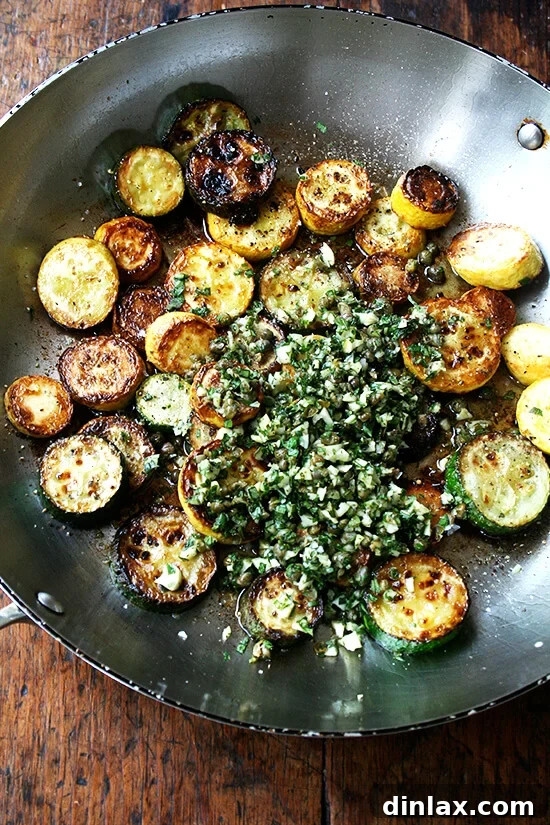 Bright Zucchini Sauté with Mint, Basil and Pine Nuts 5 The 'knife pesto' mixture being added to the golden-brown sautéed zucchini and summer squash in a pan.
