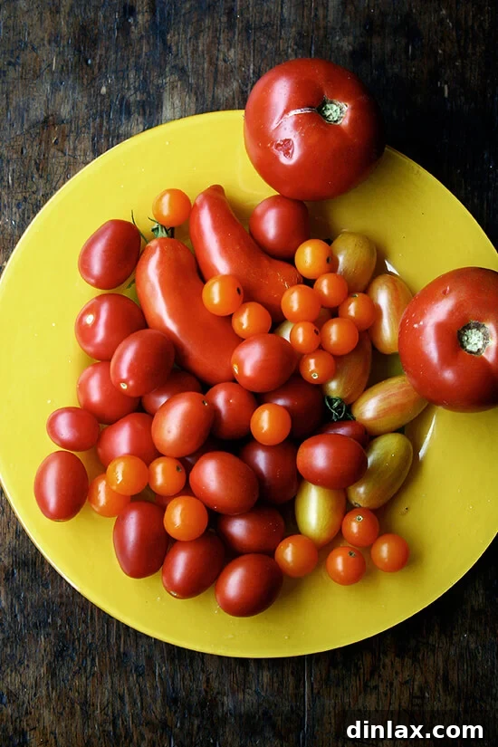 A large platter overflowing with ripe, red summer tomatoes, showcasing the bounty of the season that inspires this soup.