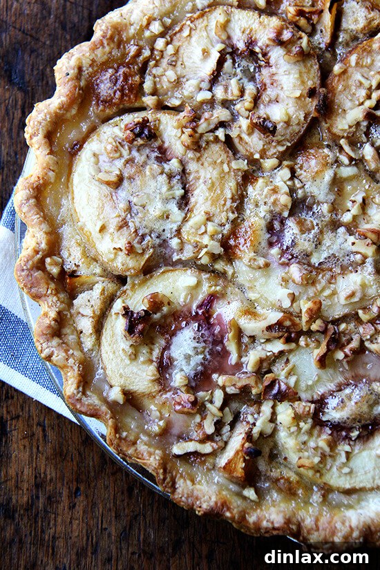 Close-up of baked German peach pie, showing the golden-brown crust, bubbly vanilla custard, and perfectly cooked peach halves. Garnish with chopped nuts.