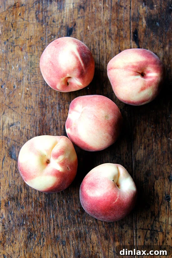 Fresh, ripe peaches on a cutting board, ready for preparation for a delicious summer pie.