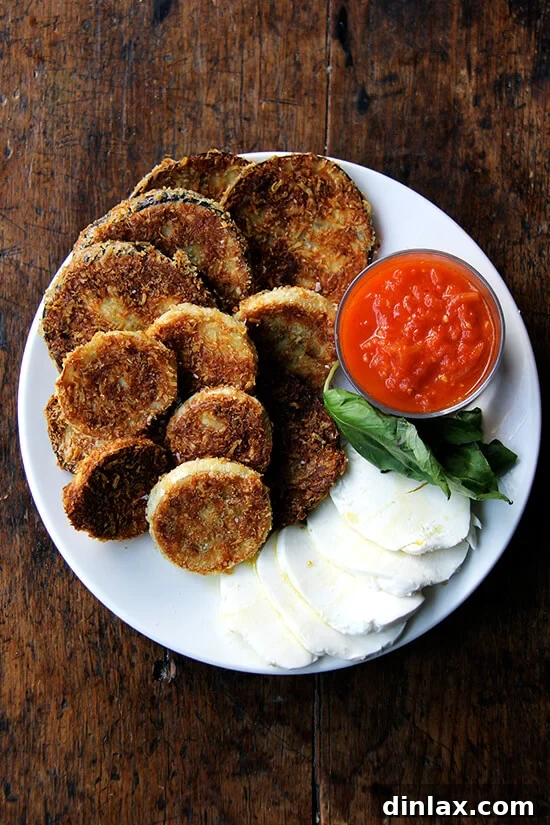 A close-up plate of deconstructed eggplant parmesan, showcasing the crispy texture and fresh toppings