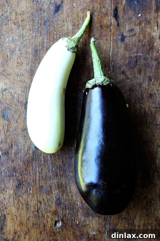 two fresh eggplants on a wooden table, waiting to be prepared