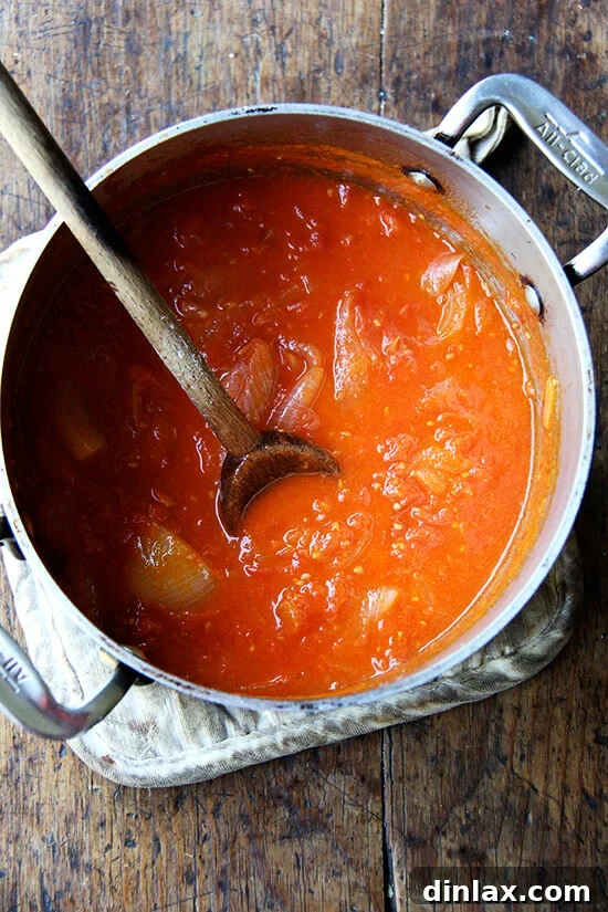 Marcella Hazan tomato sauce simmering in a pot with a whole onion