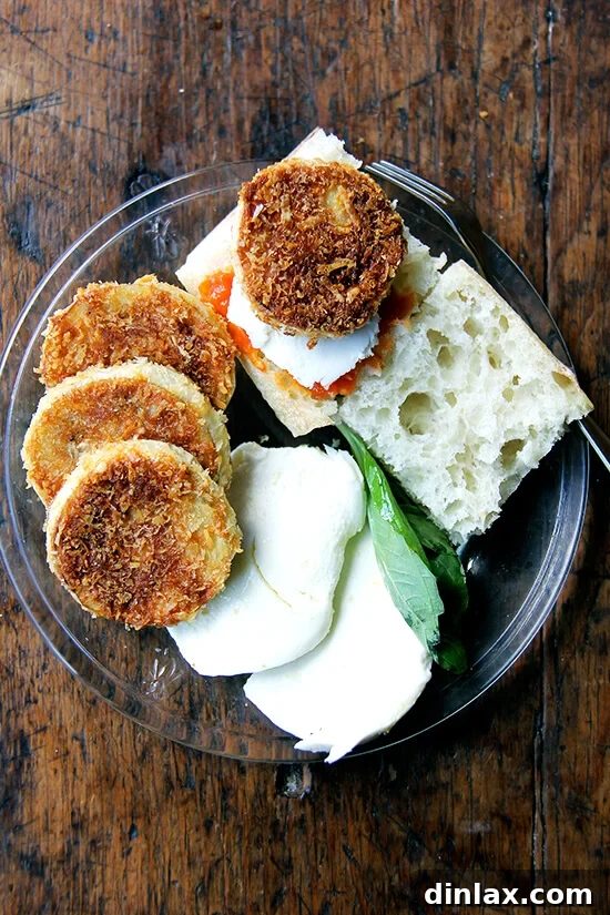 A plate of crispy eggplant rounds, fresh tomato slices, mozzarella, basil, and crusty bread