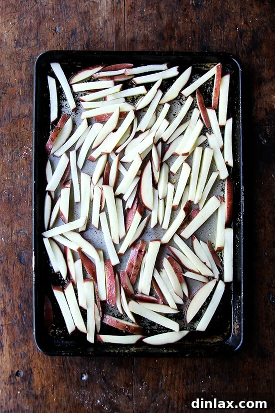 Golden Crispy Oven Fries 8 A sheet pan with seasoned potato sticks, ready for the oven.