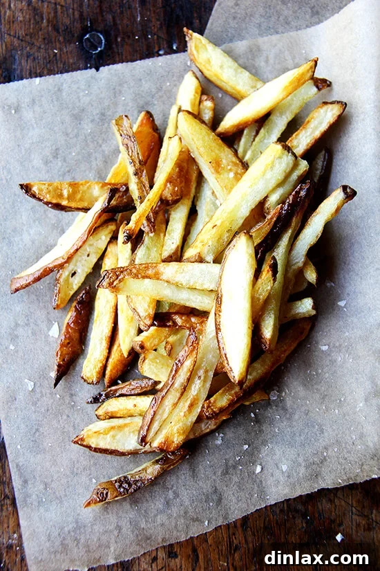 Every summer, when the potatoes start arriving in our CSA, I am blown away by their flavor, by how they need nothing more than olive oil and salt. This recipe for oven fries is especially good, especially crispy on the edges, especially creamy on the inside. // alexandracooks.com A pile of just-baked homemade French fries, sprinkled with flaky sea salt.