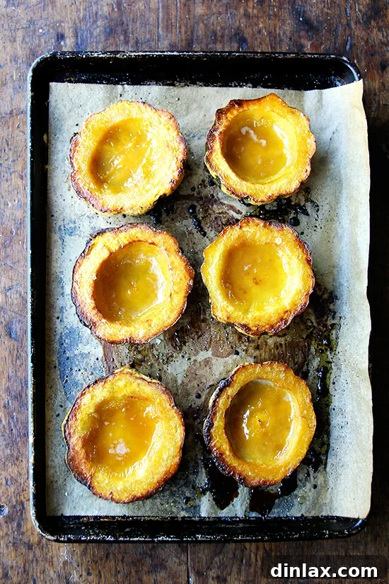 The maple-butter in this simple roasted acorn squash alone is delicious. It also encouraged some nice caramelization on the top surfaces. // alexandracooks.com A close-up of six roasted acorn squash halves on a sheet pan, glistening with caramelized maple butter.
