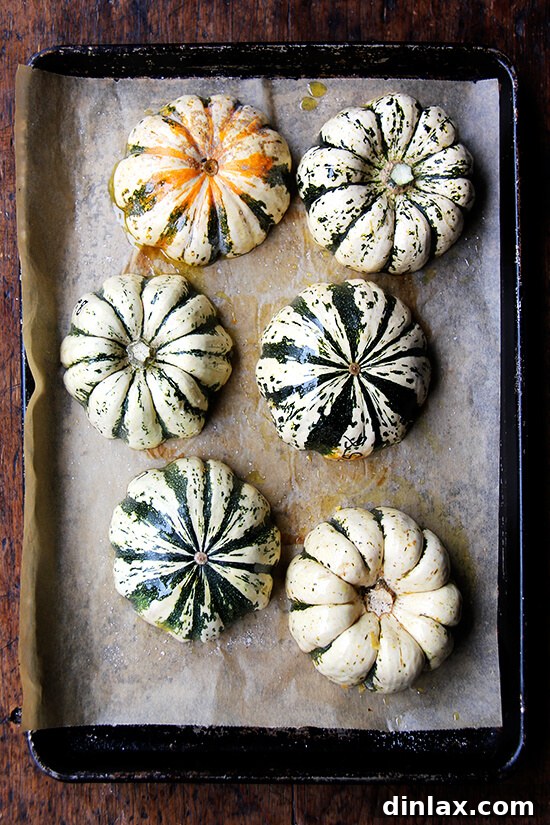 Caramelized Maple Acorn Squash 8 Six acorn squash halves, meticulously arranged cut-side down on a parchment-lined baking sheet, awaiting roasting.