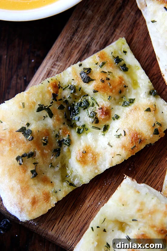 A freshly baked herbed flatbread, sliced into manageable portions, artfully arranged on a wooden board.