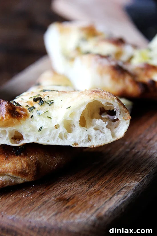 A close-up, side view of a golden-brown herbed flatbread, showcasing its impressive oven spring and airy texture.