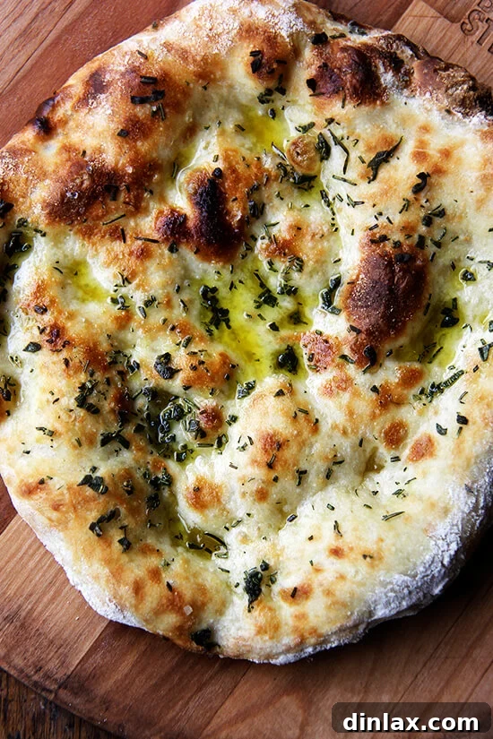 Just-baked herbed flatbread, golden and fragrant, rests on a wooden board.