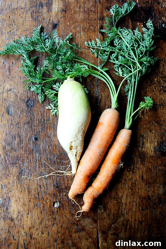 Fresh carrots and daikon radish, vibrant and ready to be sliced for a quick pickle, laid out on a clean surface.