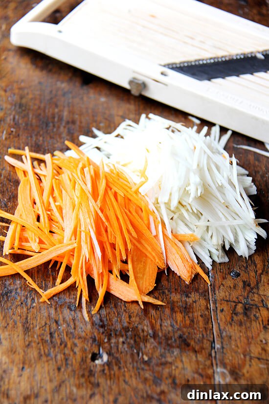 Finely julienned carrots and daikon radish, perfectly sliced for quick pickling, shown in a bowl ready for the pickling liquid.