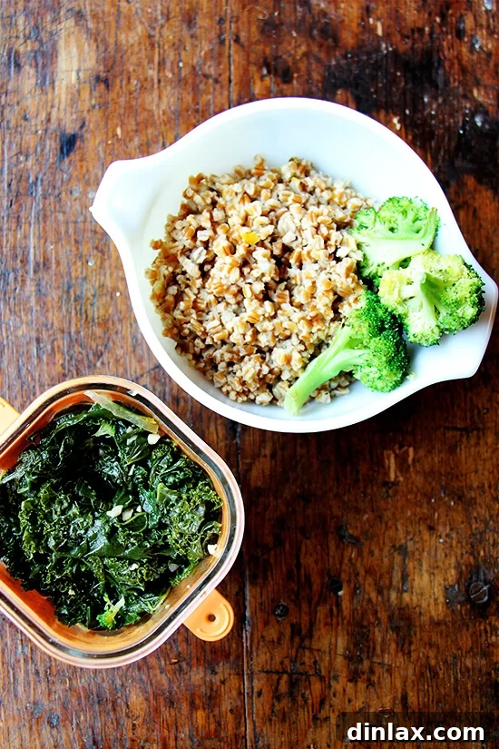 A selection of cooked leftovers including fluffy wheat berries, vibrant green sautéed kale, and tender steamed broccoli, neatly arranged in a bowl, ready to be re-steamed for a gourmet grain bowl.
