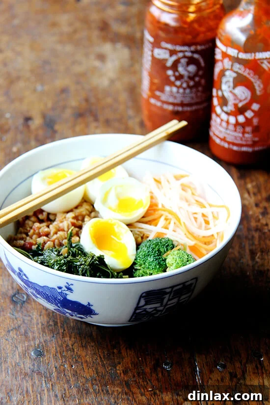 A close-up of a delicious grain bowl, generously drizzled with rich teriyaki sauce and crowned with two perfectly cooked soft-boiled eggs, suggesting a hearty and flavorful meal, enhanced with optional hot sauce.