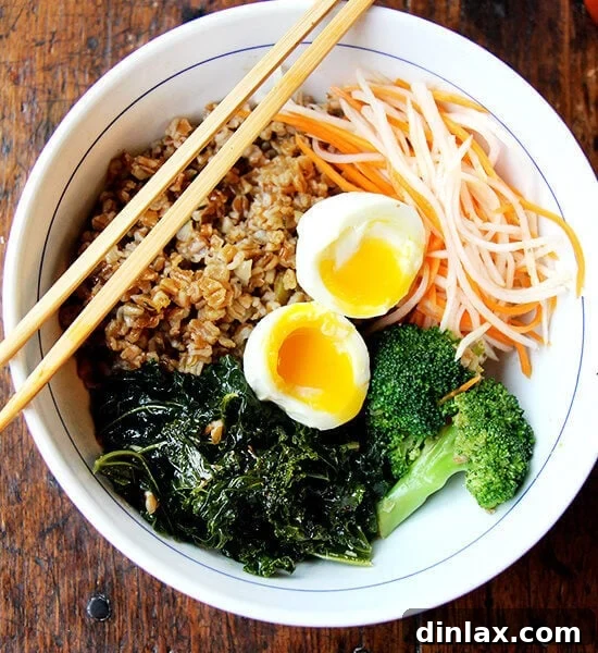 A beautifully arranged leftover grain bowl with glossy teriyaki sauce, vibrant quick-pickled carrots and daikon, and a perfectly soft-boiled egg, ready to be enjoyed.