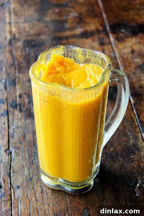 Hearty Farro Risotto with Autumn Squash and Kale 5 A food processor bowl filled with smooth, vibrant orange butternut squash purée, indicating a silky, lump-free consistency achieved after blending.