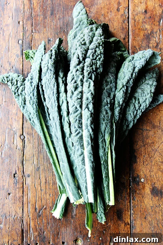 Hearty Farro Risotto with Autumn Squash and Kale 7 A generous bunch of fresh green kale leaves resting on a wooden cutting board, with some leaves already prepped, ready for preparation and slicing.