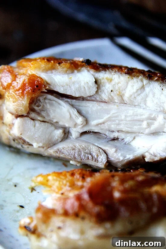 A chicken thigh on a plate, cut in half to reveal its juicy interior.