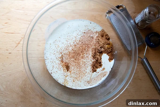 Golden Roasted Butternut Bliss Pie 9 A large mixing bowl containing heavy cream, beaten eggs, sugar, salt, and a blend of warm spices, before being whisked.