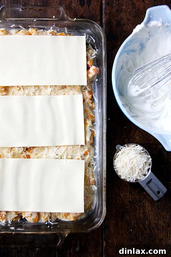 An unbaked butternut squash lasagna filling a 9x13-inch pan, showing layered ingredients.