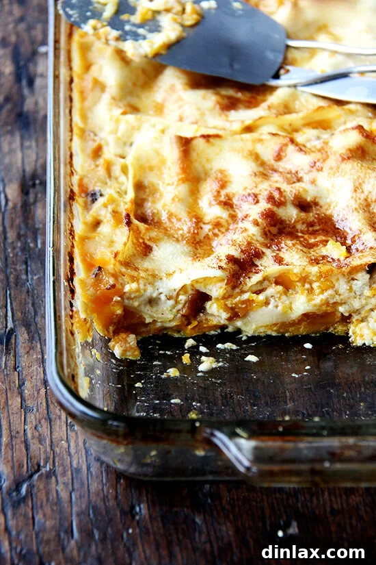 A freshly baked butternut squash lasagna, with one enticing slice carefully removed from the pan.