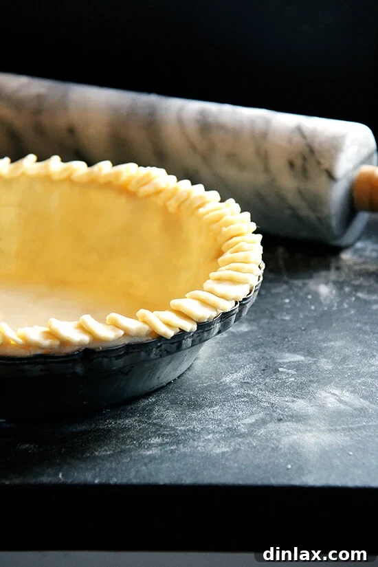 An unbaked pie with a beautifully crimped and decorative crust, ready for the oven.
