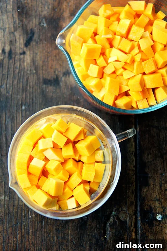 Several clear measuring cups are filled to the brim with vibrant orange diced butternut squash.