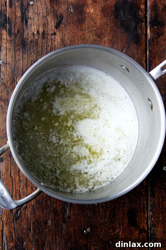 A saucepan on the stovetop contains melted butter and fragrant minced garlic.