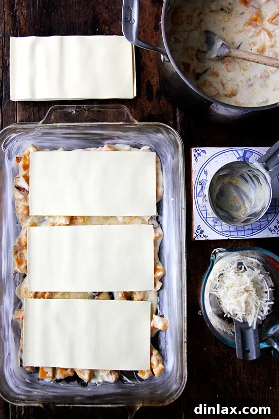 A 9x13-inch baking pan with a thin layer of béchamel sauce and three dry lasagna sheets.