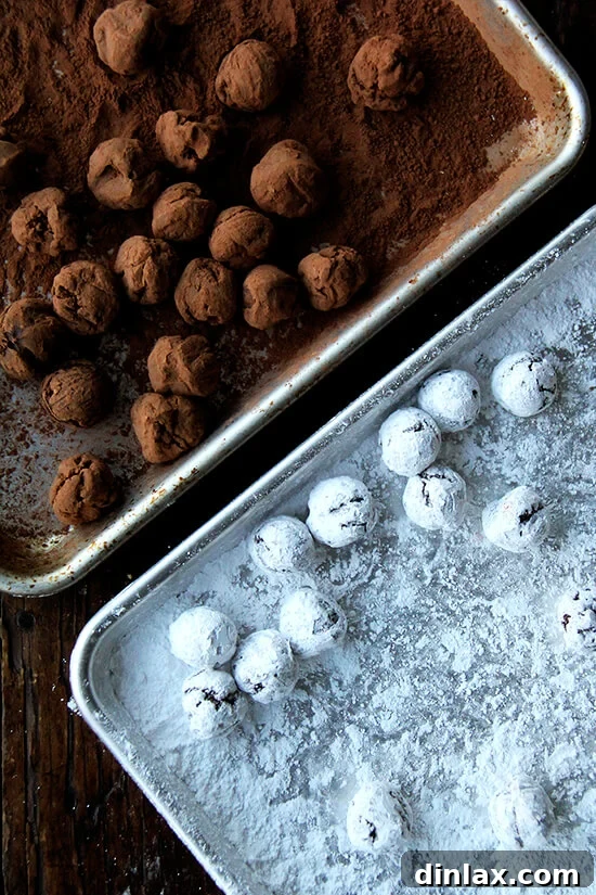Decadent Grand Marnier Chocolate Truffles 11 Two sheet pans side-by-side, one displaying chocolate truffles generously dusted with powdered sugar, and the other with truffles coated in unsweetened cocoa powder, offering two classic finishing styles.