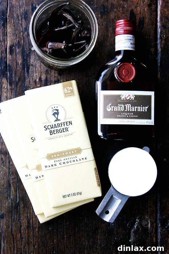 Decadent Grand Marnier Chocolate Truffles 3 Assortment of high-quality chocolate bars, heavy cream, vanilla beans, and a bottle of Grand Marnier liqueur, laid out on a table as ingredients for truffles.