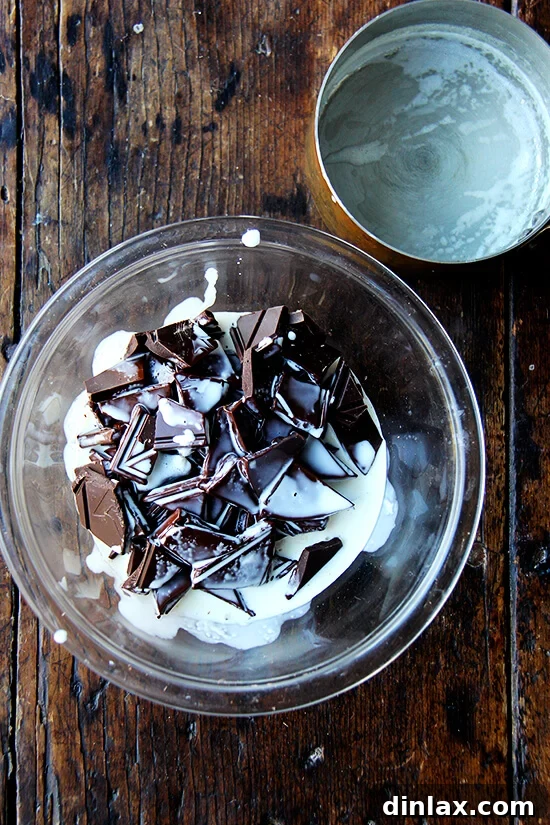Decadent Grand Marnier Chocolate Truffles 4 A stream of hot, heavy cream being poured over a bowl of chopped chocolate, initiating the ganache-making process.