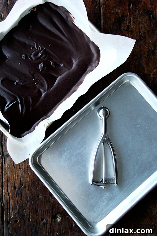 Decadent Grand Marnier Chocolate Truffles 7 A baking sheet filled with firm chocolate truffle mixture, alongside an empty sheet pan, both ready for scooping. A #100 scoop rests in the empty pan.