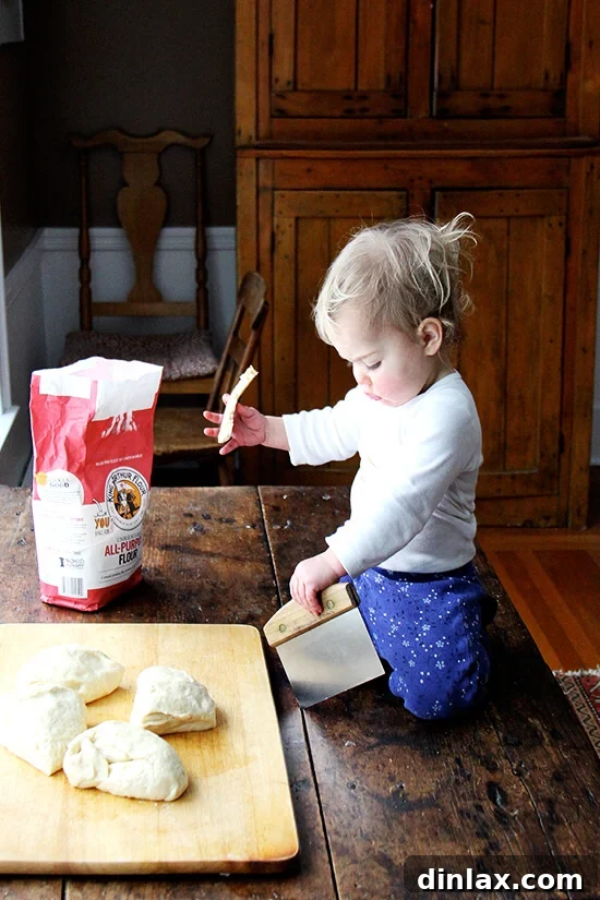 A child, Wren, playfully assisting with the Challah bread dough shaping, highlighting family involvement.