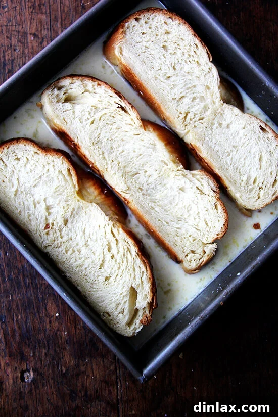 Slices of Challah bread soaking in a rich custard bath, preparing for French toast.