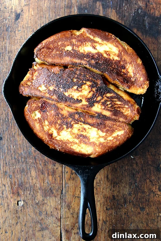 Golden-brown Challah bread French toast sizzling in a skillet, ready to be served.