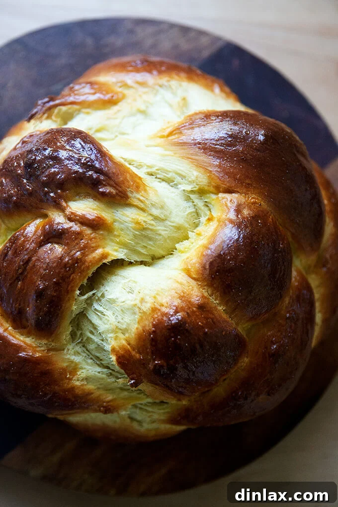 A glorious freshly baked Challah on a rustic wooden board, ready for slicing.